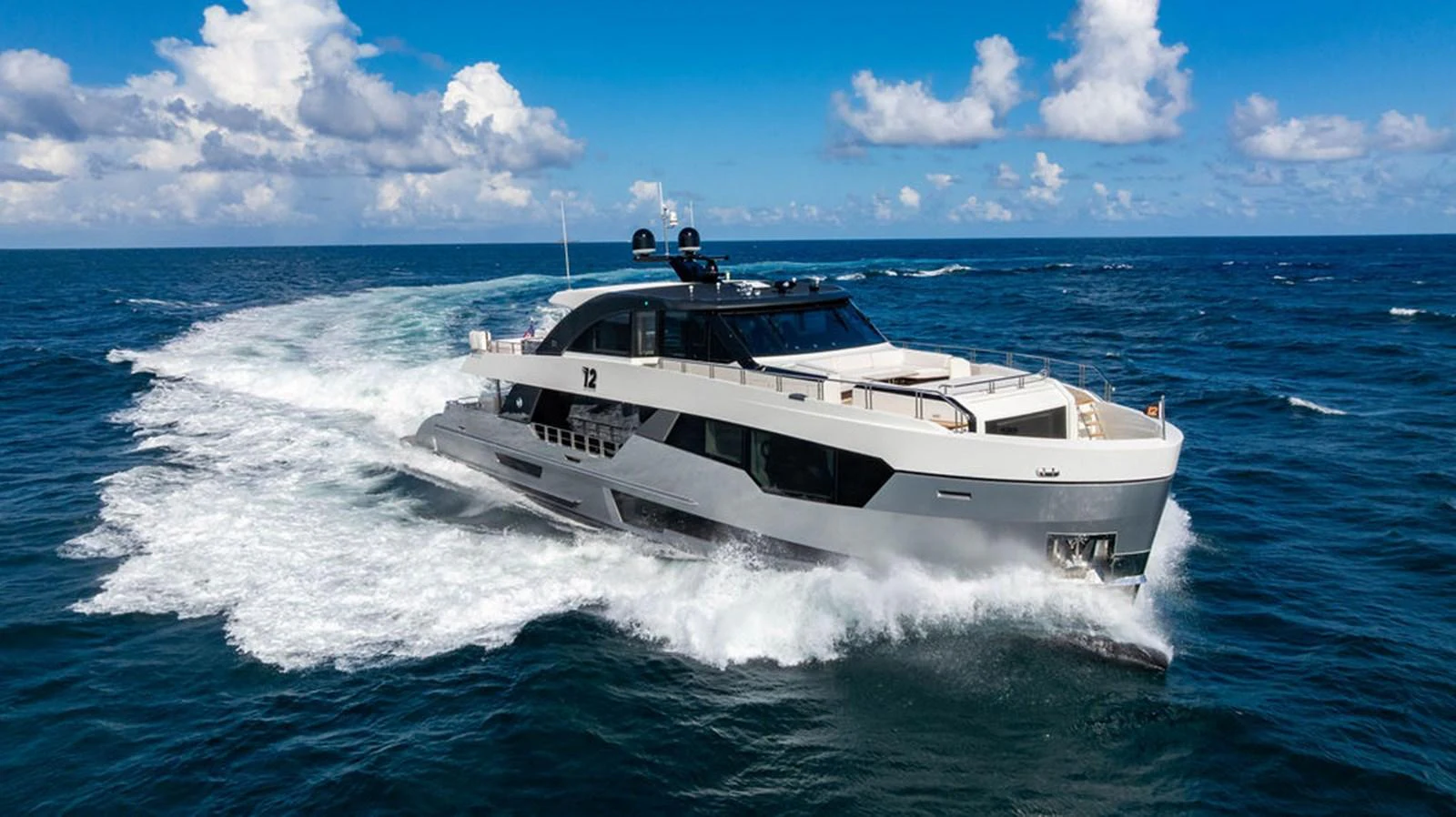 A sleek and modern yacht cruises swiftly through the open ocean under a bright blue sky. aboard M/Y 12 Yacht for Sale