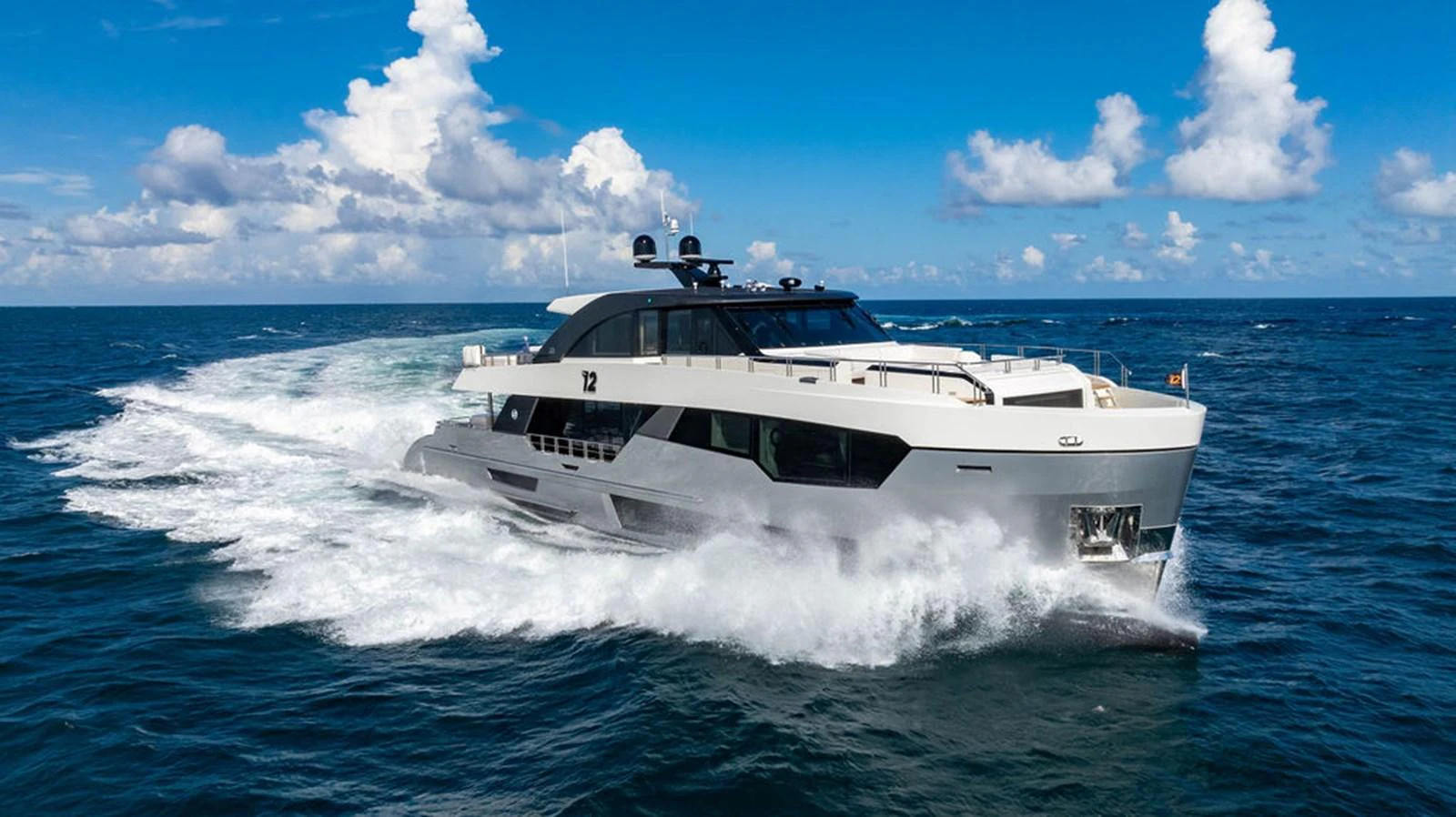 A sleek and modern yacht cruises swiftly through the open sea under a bright blue sky. aboard M/Y 12 Yacht for Sale