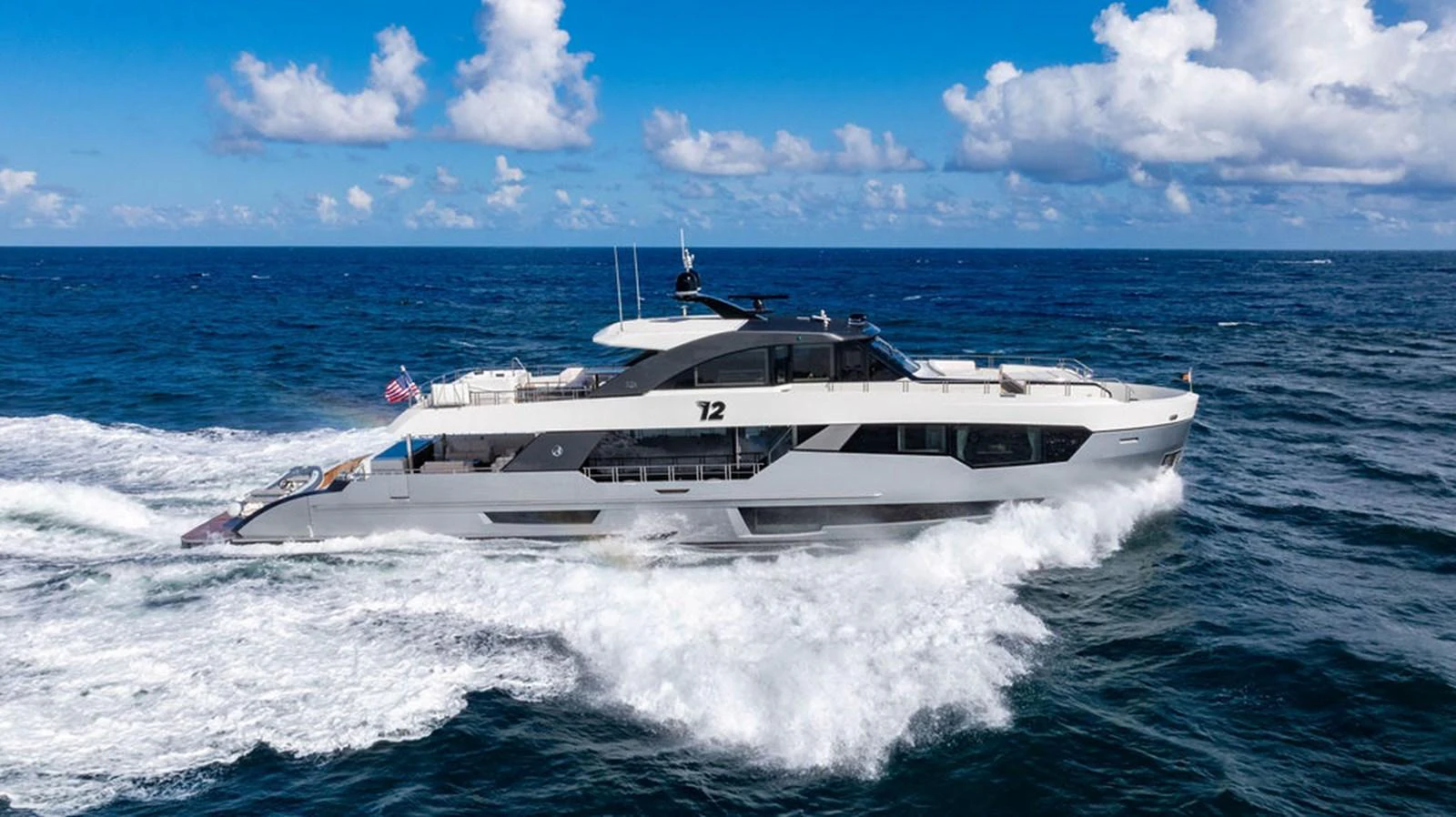 A sleek and modern yacht cruises swiftly through the open sea under a bright blue sky. aboard M/Y 12 Yacht for Sale
