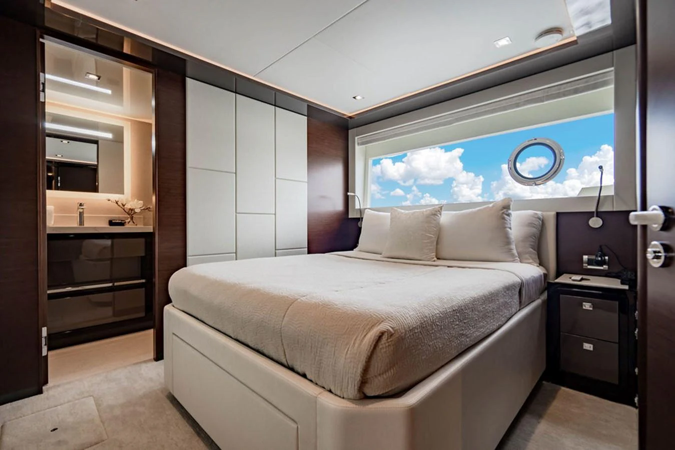 The stateroom features a plush bed with a large window offering a stunning view of the sea. aboard M/Y 12 Yacht for Sale