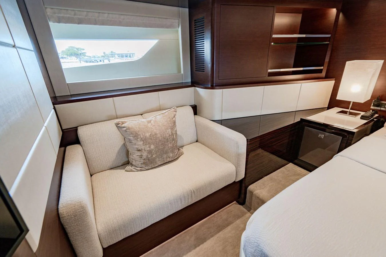 The stateroom features a cozy seating area with elegant decor and a large window for natural light. aboard M/Y 12 Yacht for Sale