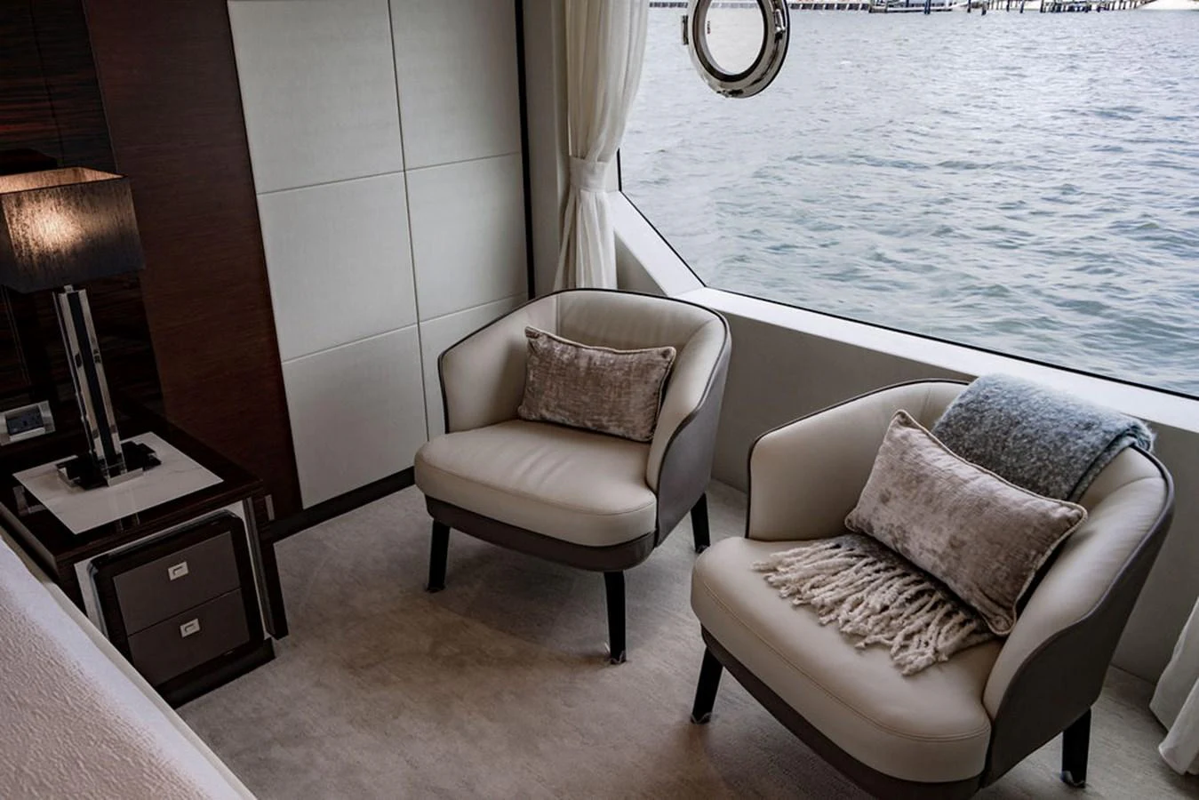 A cozy seating area with two plush armchairs and a view of the water through a large window. aboard M/Y 12 Yacht for Sale