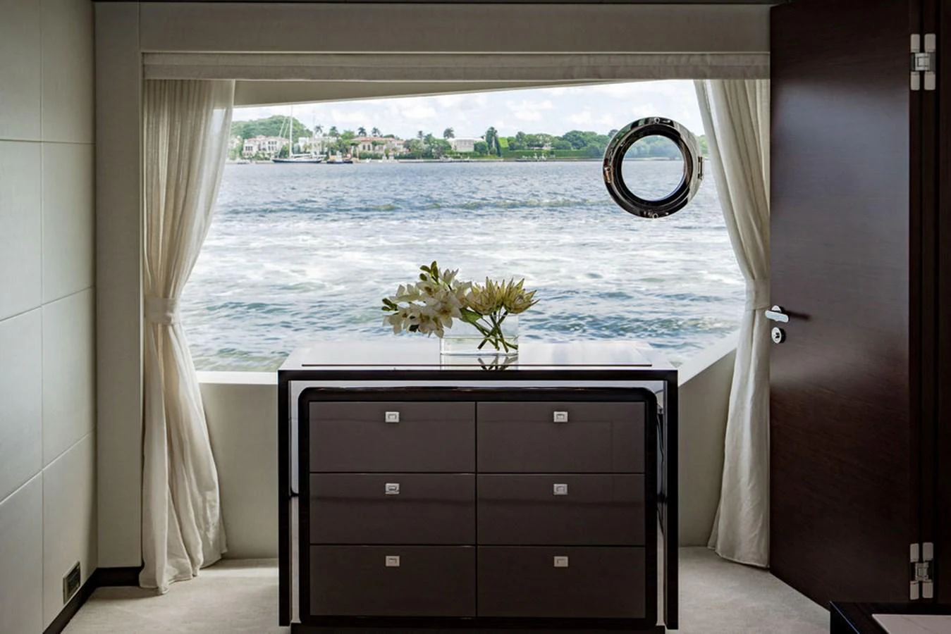 A serene interior view featuring a dresser with a picturesque window overlooking the water. aboard M/Y 12 Yacht for Sale