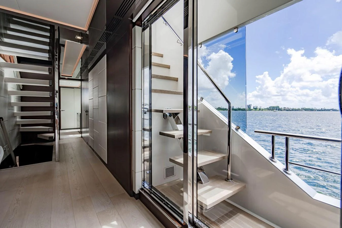 A modern yacht interior featuring a sleek staircase with a view of the water through large windows. aboard M/Y 12 Yacht for Sale