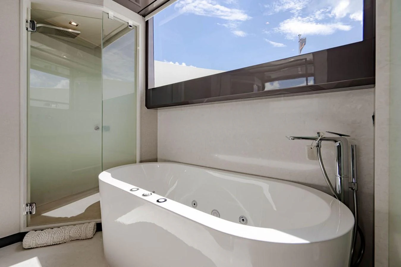 A luxurious bathroom with a modern bathtub and a large window offering a view of the sky. aboard M/Y 12 Yacht for Sale