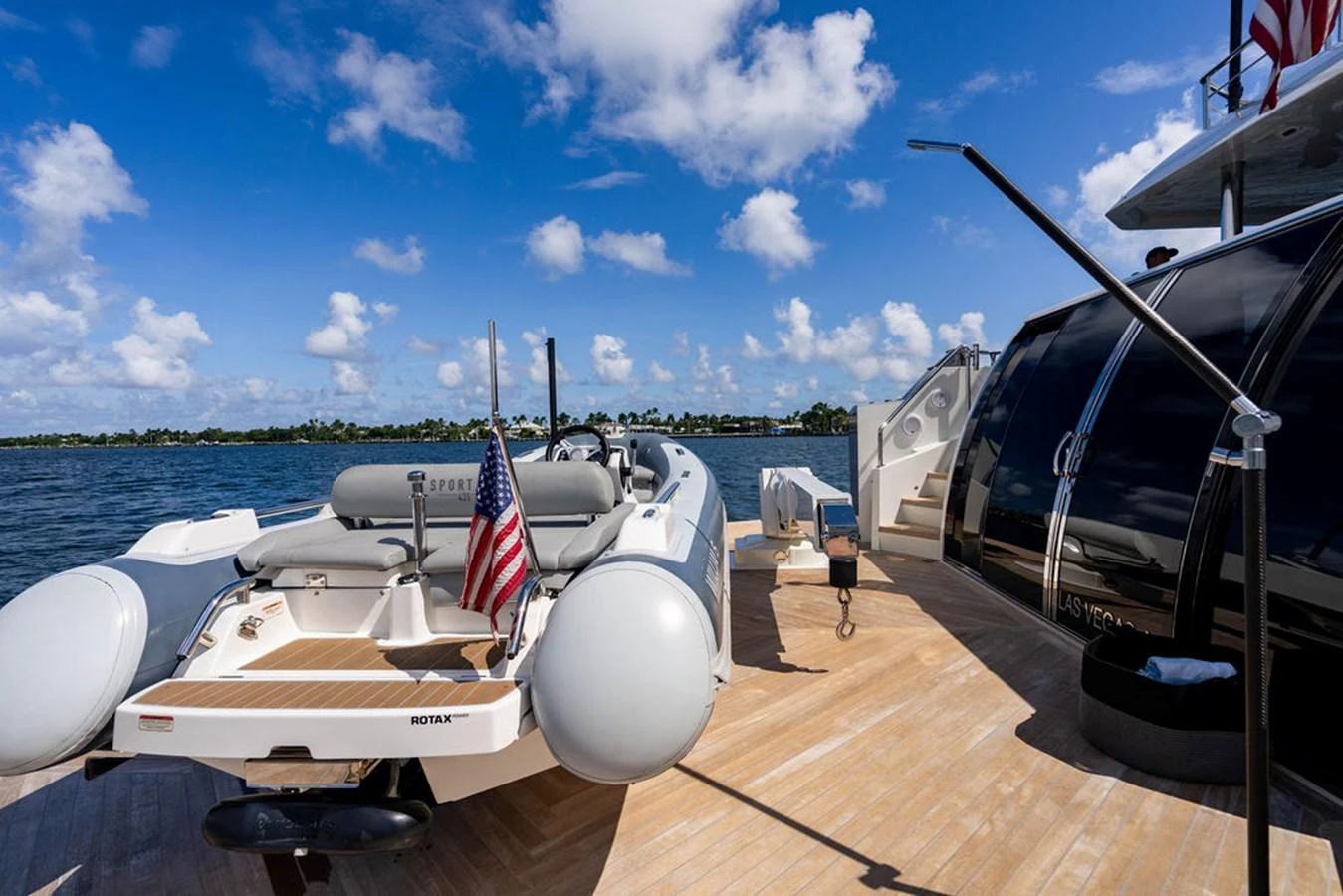 A sleek tender is docked on the deck of a luxury yacht under a bright blue sky. aboard M/Y 12 Yacht for Sale