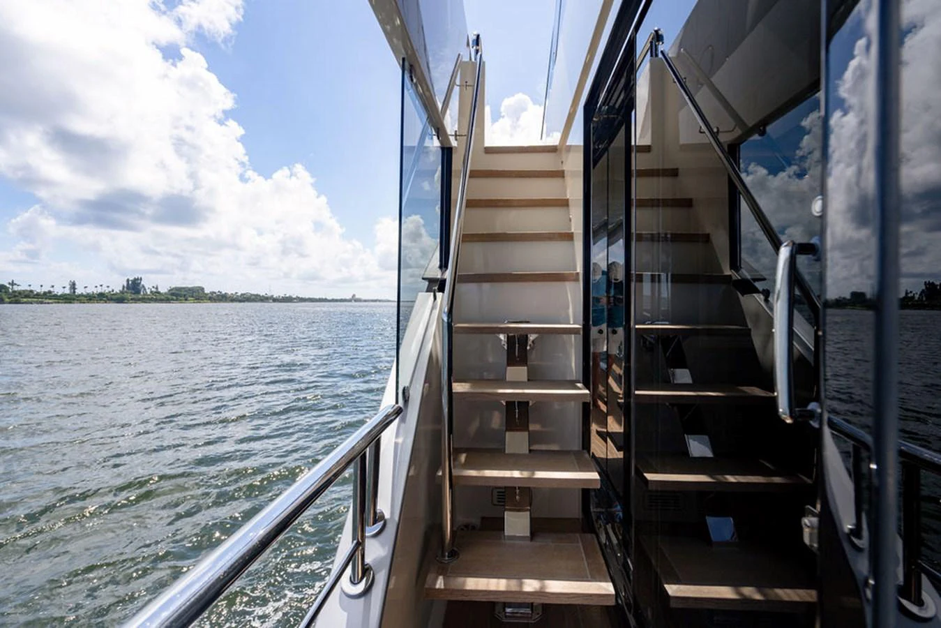 The yacht's side deck features a staircase leading to the upper level, with a view of the water and sky. aboard M/Y 12 Yacht for Sale