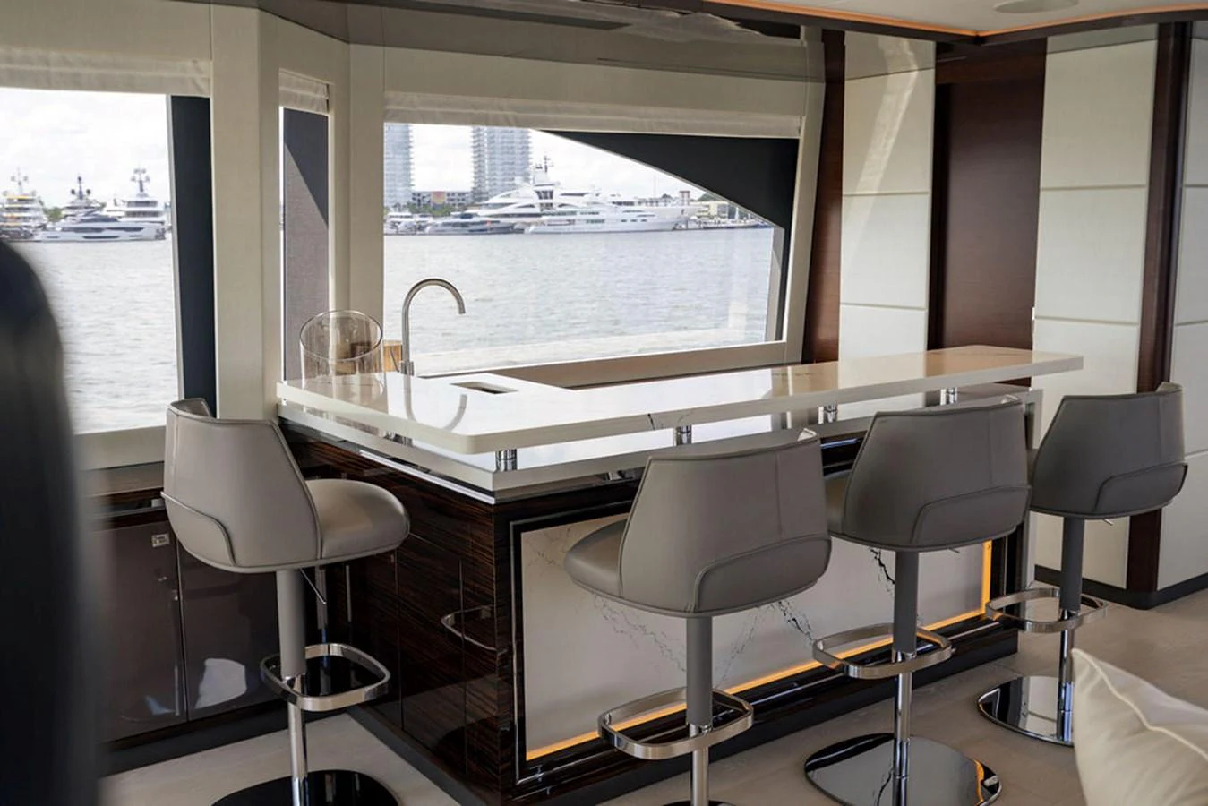 The yacht's galley features a sleek bar area with modern stools and a large window offering a view of the marina. aboard M/Y 12 Yacht for Sale