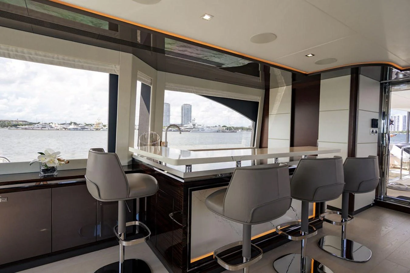 The yacht's interior features a sleek bar area with modern seating and large windows offering scenic views. aboard M/Y 12 Yacht for Sale