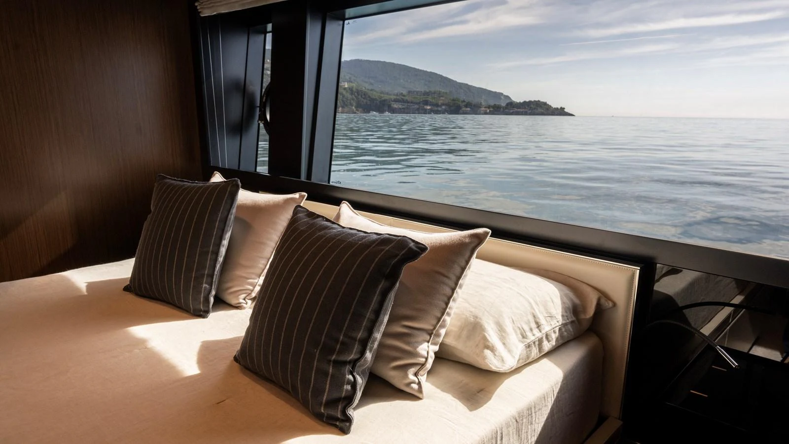 The stateroom offers a serene view of the sea through large windows, complemented by plush pillows on a comfortable bed. aboard GIO4 Yacht for Sale