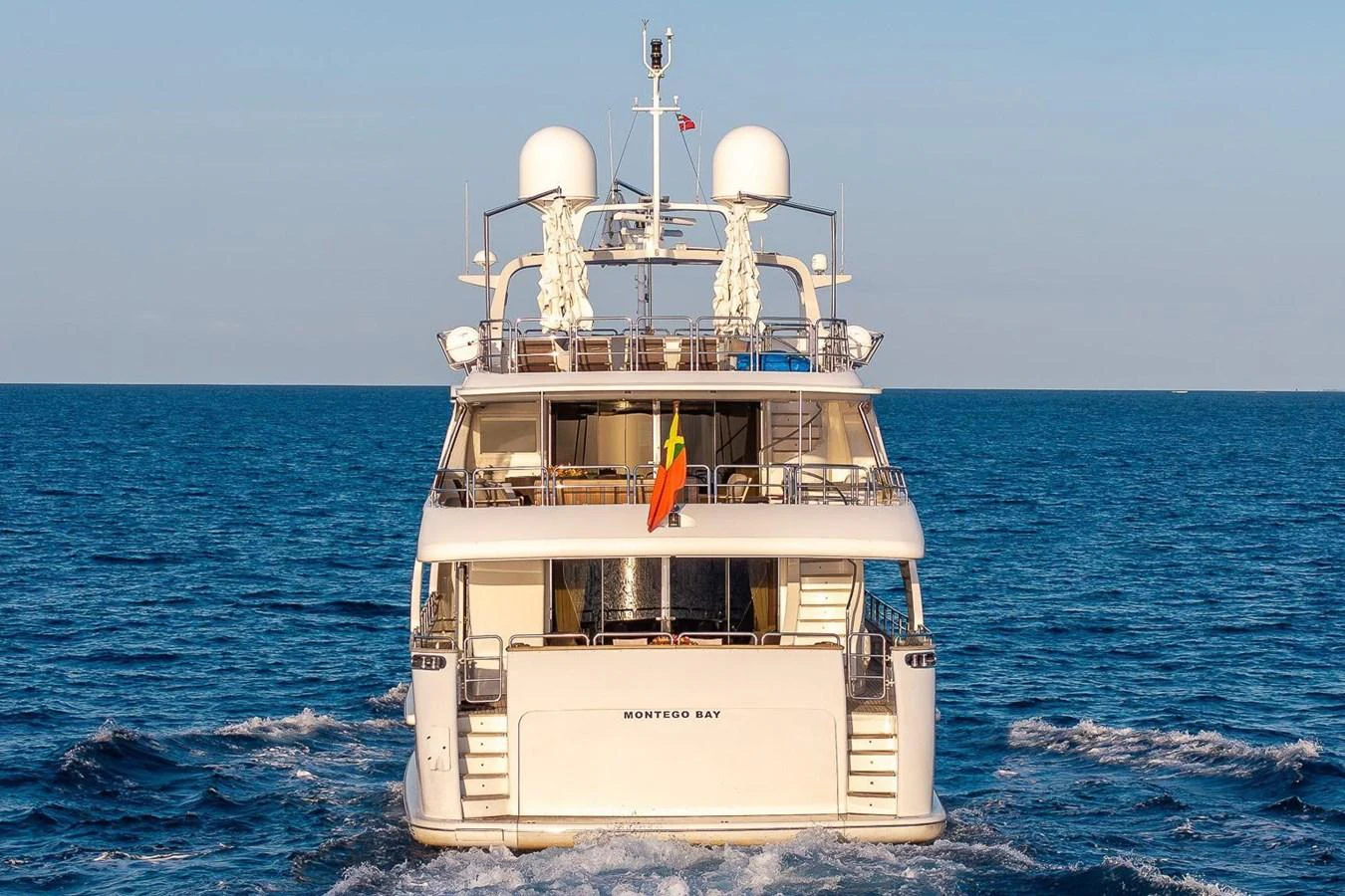 The yacht is seen from the rear, cruising through calm blue waters. aboard GOTTA GO Yacht for Sale