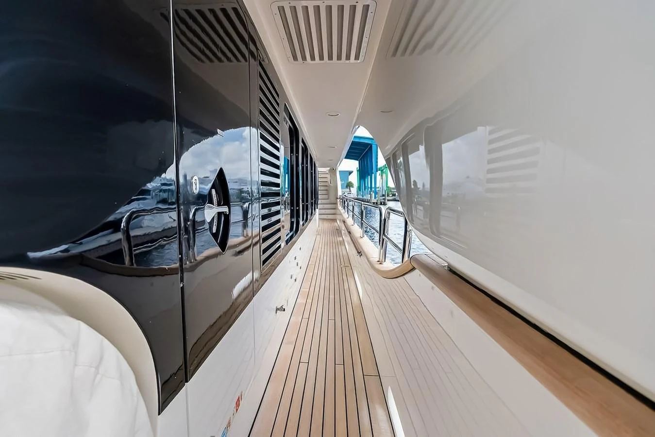 The side deck offers a sleek and modern passageway with elegant wooden flooring and reflective surfaces. aboard GOTTA GO Yacht for Sale