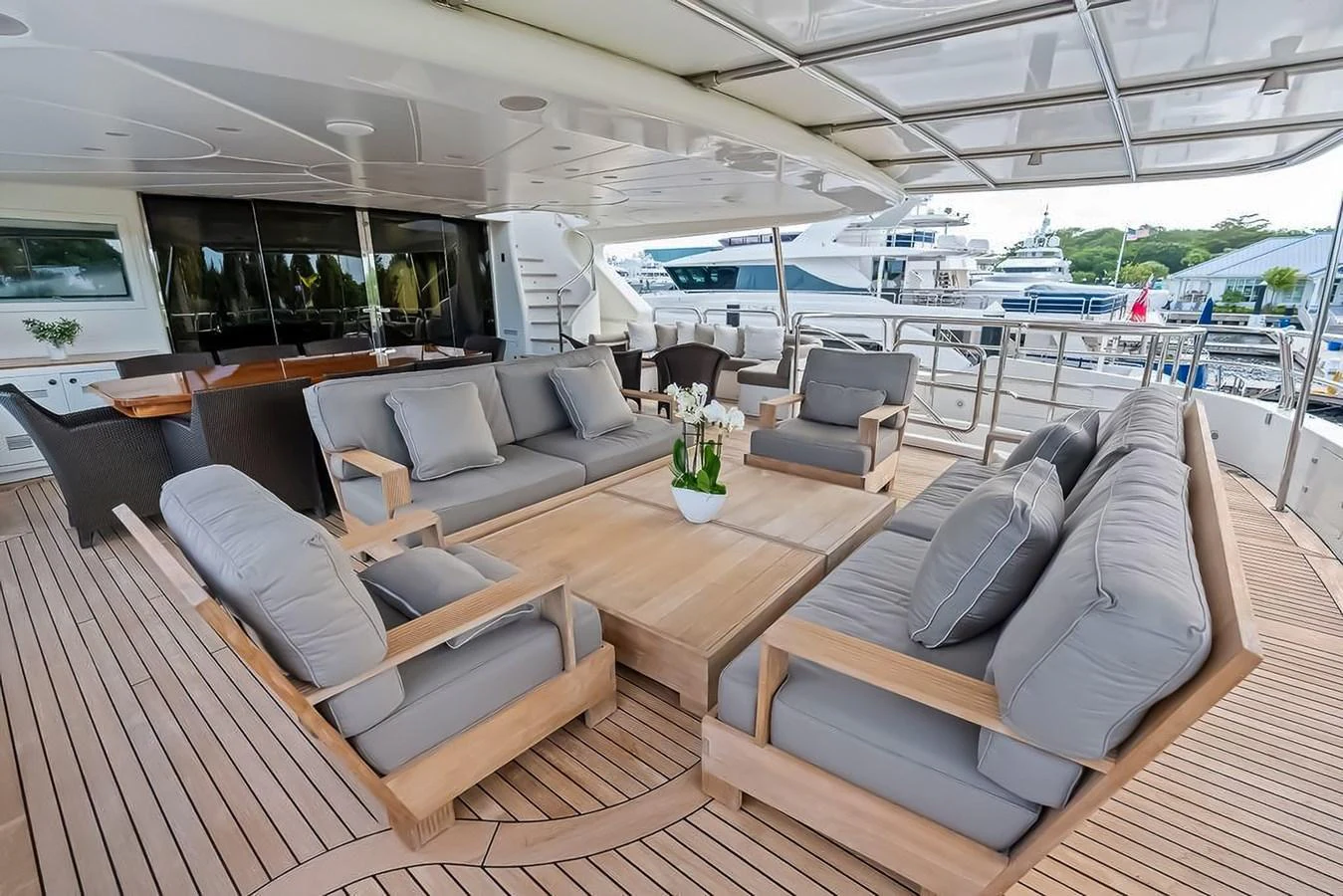 The aft deck features a spacious and elegant seating area with plush cushions and a large wooden table, perfect for outdoor relaxation and dining. aboard GOTTA GO Yacht for Sale