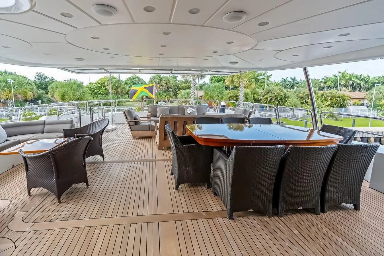 The aft deck features a spacious seating area with wicker chairs and a large dining table, perfect for outdoor gatherings. aboard GOTTA GO Yacht for Sale