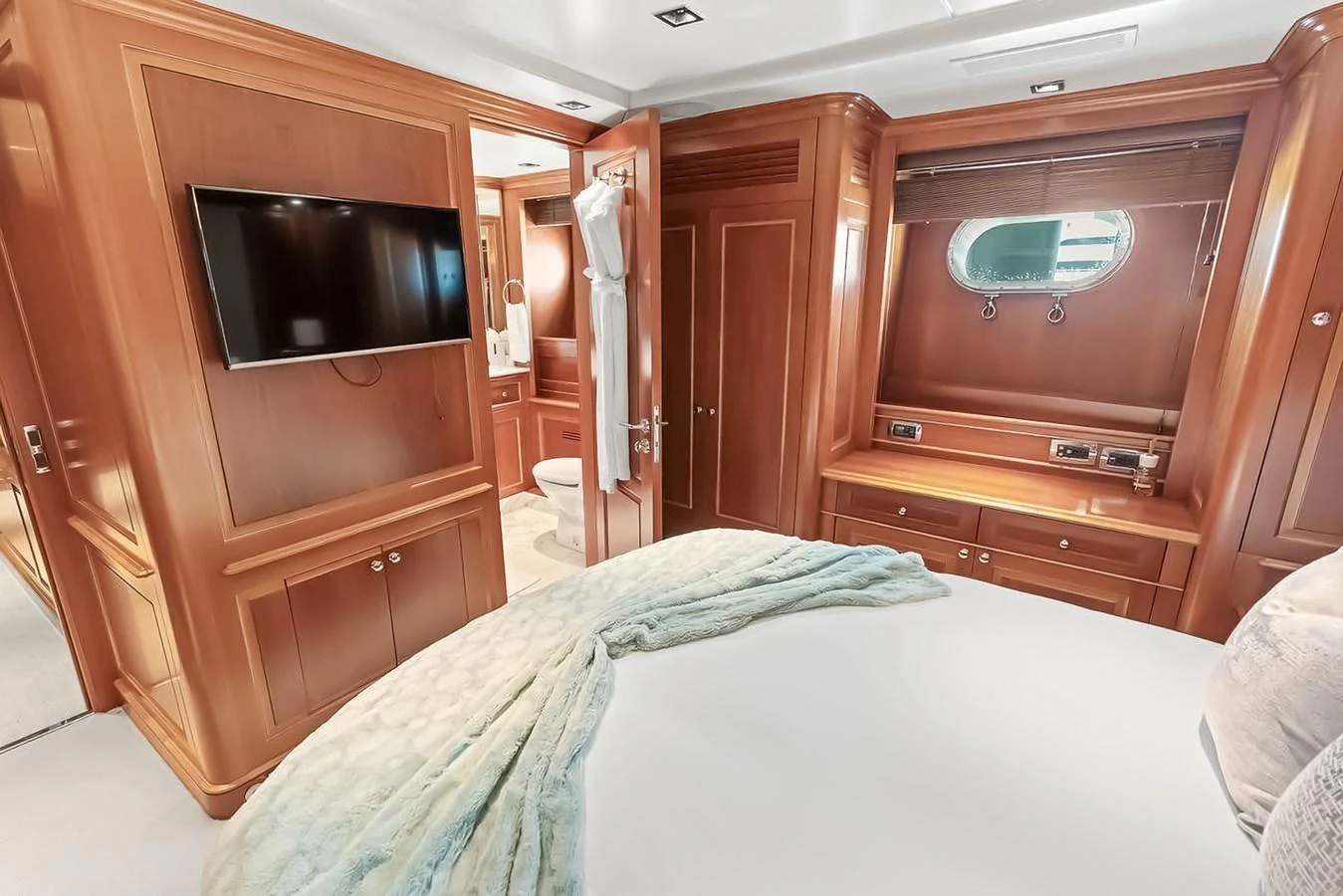 A luxurious stateroom featuring rich wood paneling, a flat-screen TV, and an ensuite bathroom. aboard GOTTA GO Yacht for Sale