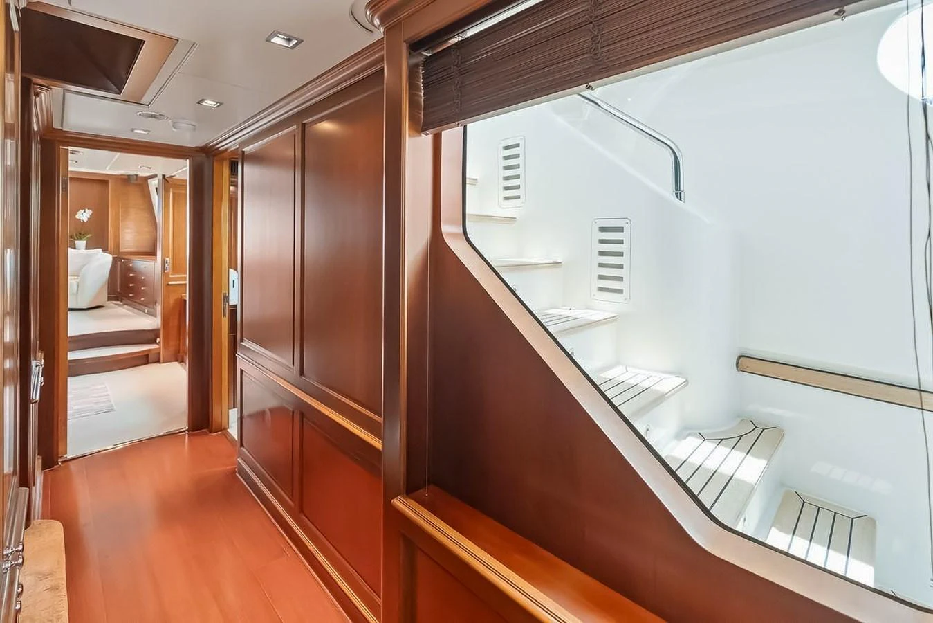 The image showcases a luxurious yacht interior with polished wood paneling and a well-lit staircase. aboard GOTTA GO Yacht for Sale