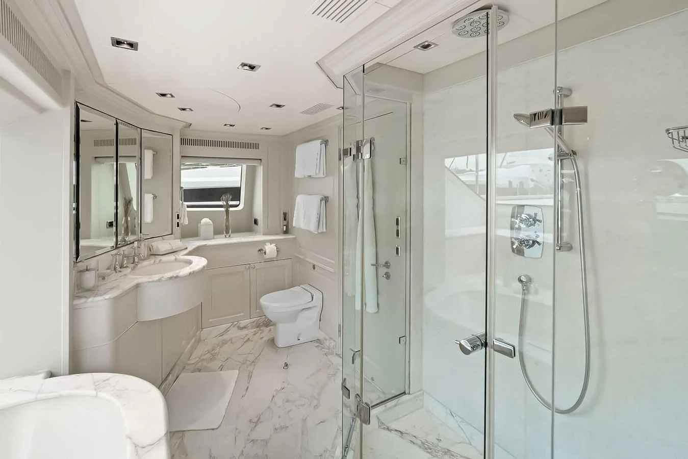 This luxurious yacht bathroom features elegant marble flooring and a spacious glass-enclosed shower. aboard GOTTA GO Yacht for Sale
