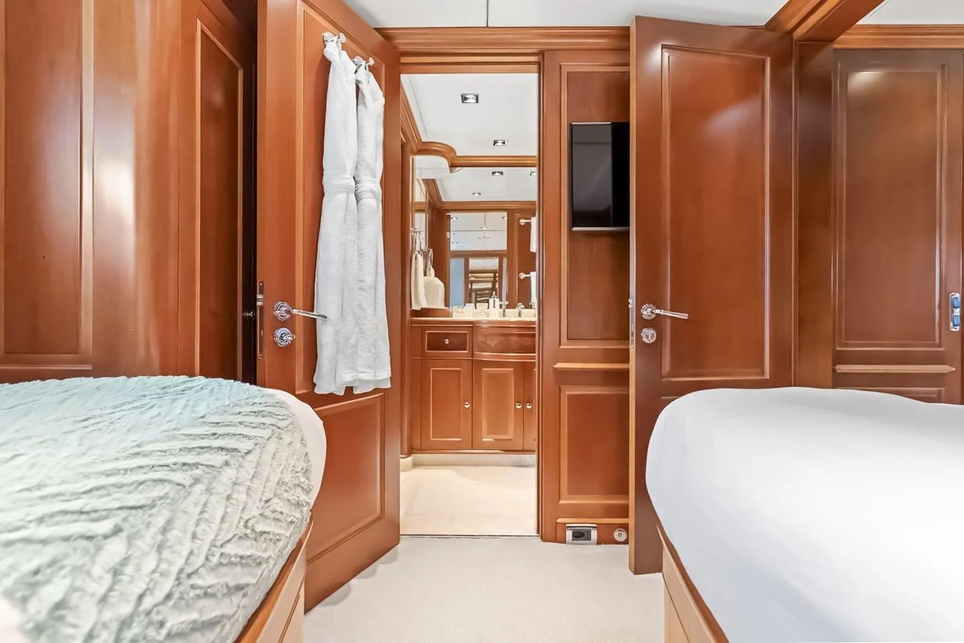 The guest stateroom features elegant wood paneling and a view into the ensuite bathroom. aboard GOTTA GO Yacht for Sale