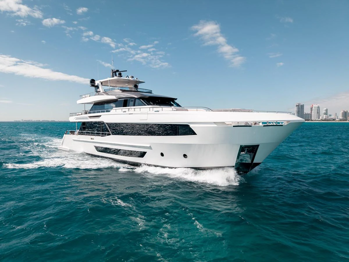 A sleek and modern yacht cruises through clear blue waters with a cityscape in the background. aboard OCEAN ALEXANDER 35P05 Yacht for Sale