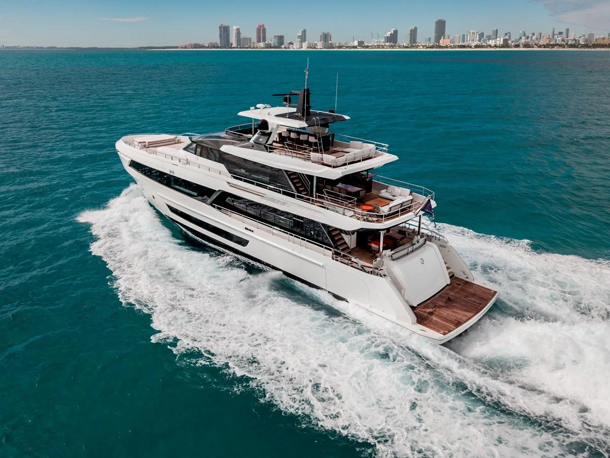 A sleek and modern yacht cruises through turquoise waters with a city skyline in the background. aboard OCEAN ALEXANDER 35P05 Yacht for Sale