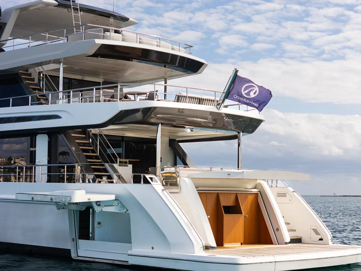 The yacht's aft deck showcases a sleek design with multiple levels and a flag waving in the breeze. aboard OCEAN ALEXANDER 35P05 Yacht for Sale