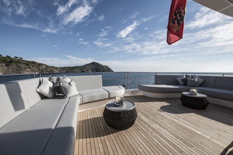 a deck with a large body of water and a large red flag aboard BERCO VOYAGER Yacht for Charter