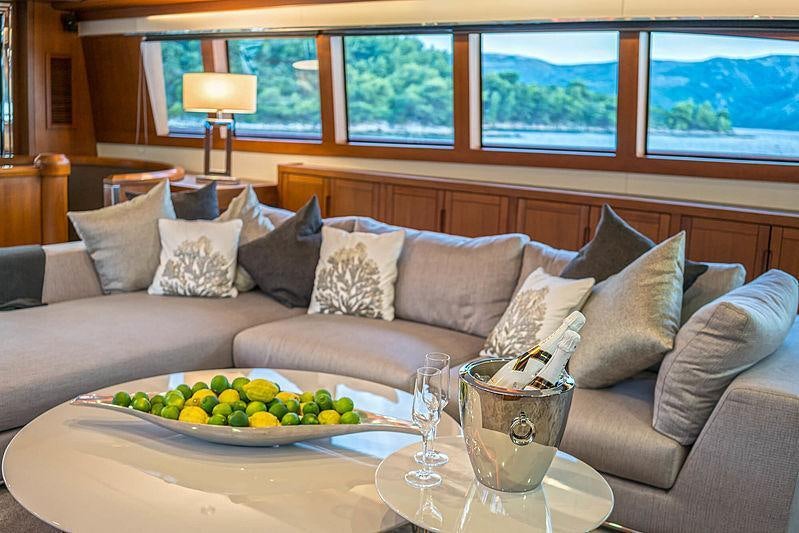 a couch with a table and a glass of wine on it aboard SAN LIMI Yacht for Charter