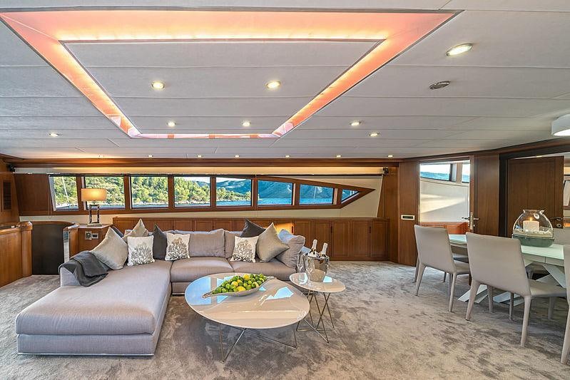 a living room with a large sofa and a large window aboard SAN LIMI Yacht for Charter