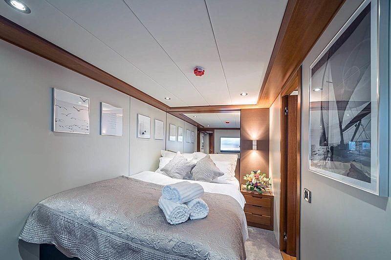 a bedroom with a bed and a window aboard SAN LIMI Yacht for Charter
