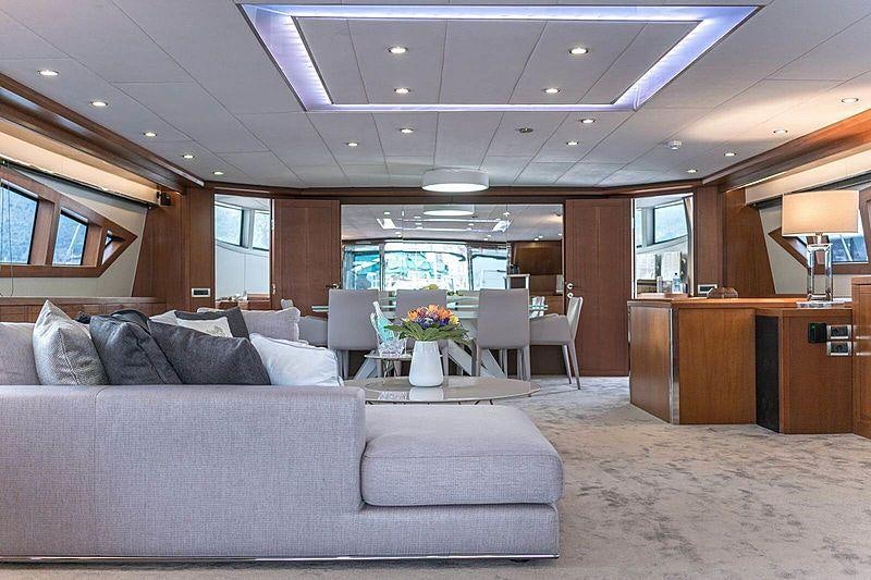 a large living room with a large sofa and a large window aboard SAN LIMI Yacht for Charter