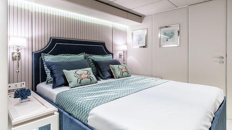a bed with a blue and white comforter and pillows aboard BUNDALONG Yacht for Charter