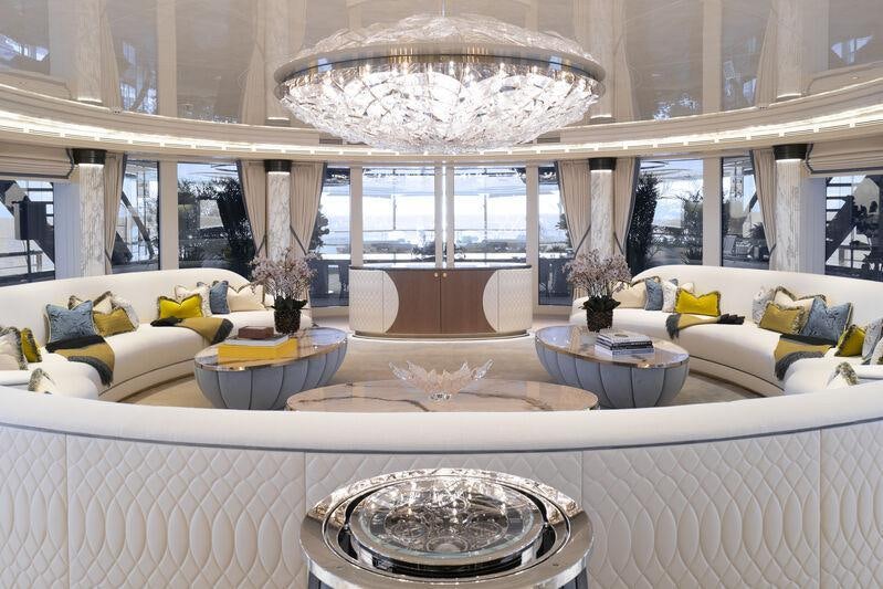 a large white room with a chandelier and a white couch aboard AHPO Yacht for Charter