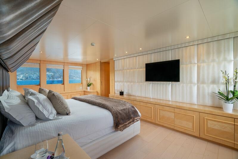 a room with a bed and a television aboard ATOM Yacht for Charter