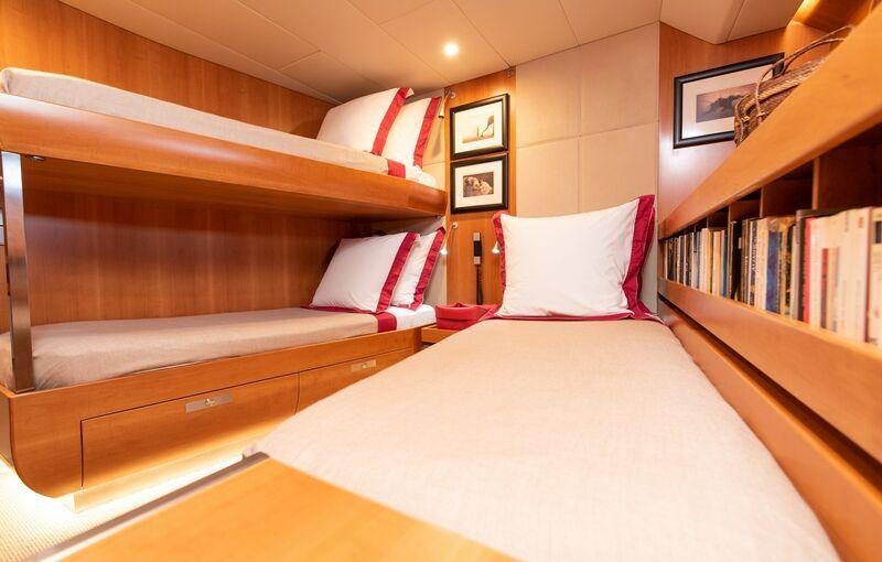 a bed with a white pillow and red and white pillows aboard SILVERTIP Yacht for Charter