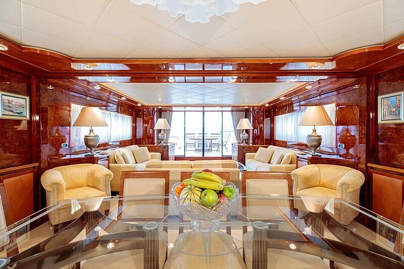 a large living room with a large glass table and a large window aboard OVAL Yacht for Charter