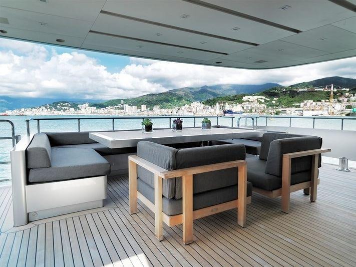 a room with a couch and a table and chairs on a deck aboard NAIA Yacht for Charter