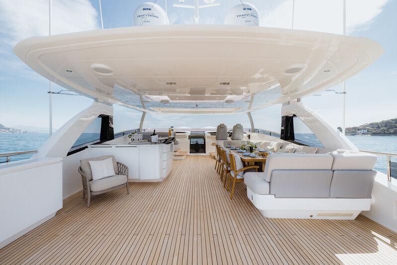 a large white yacht with chairs and tables on a deck aboard RIVIERA LIVING Yacht for Charter