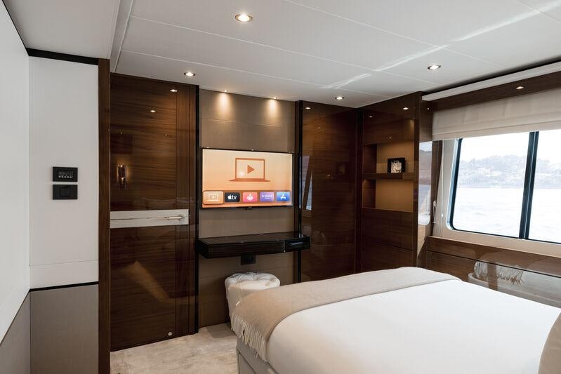 a room with a bed and a television aboard RIVIERA LIVING Yacht for Charter
