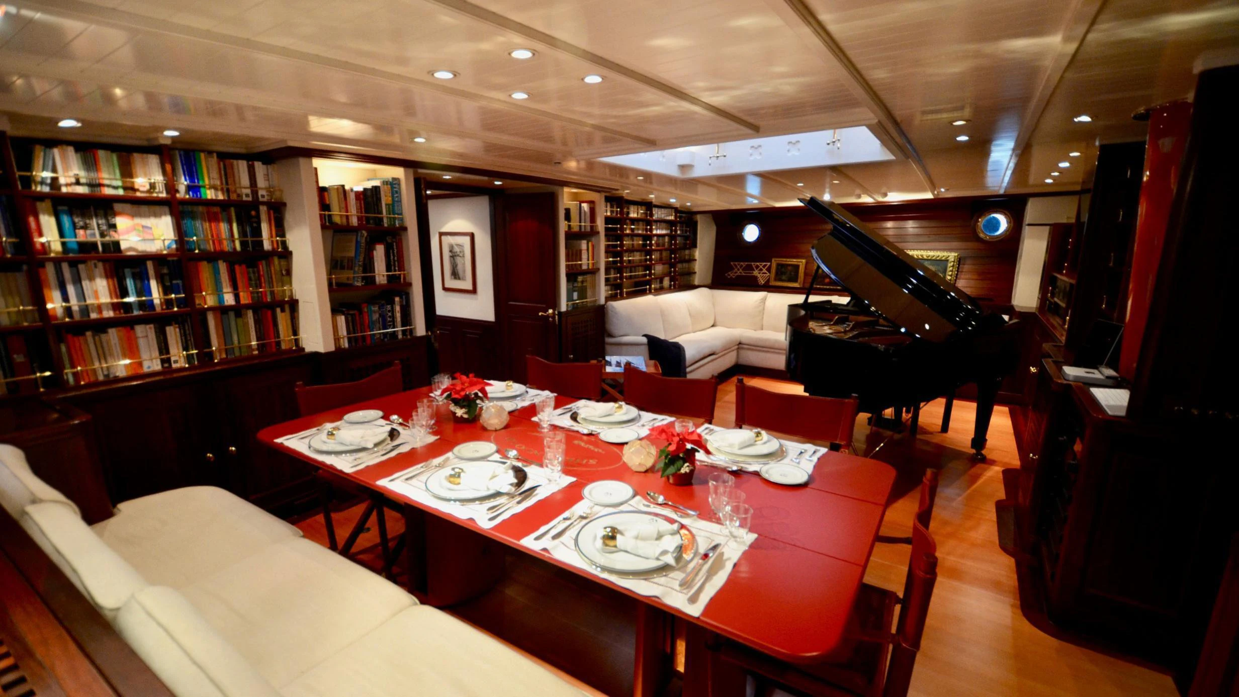 a room with a piano and a table with plates and chairs aboard SHENANDOAH OF SARK Yacht for Charter