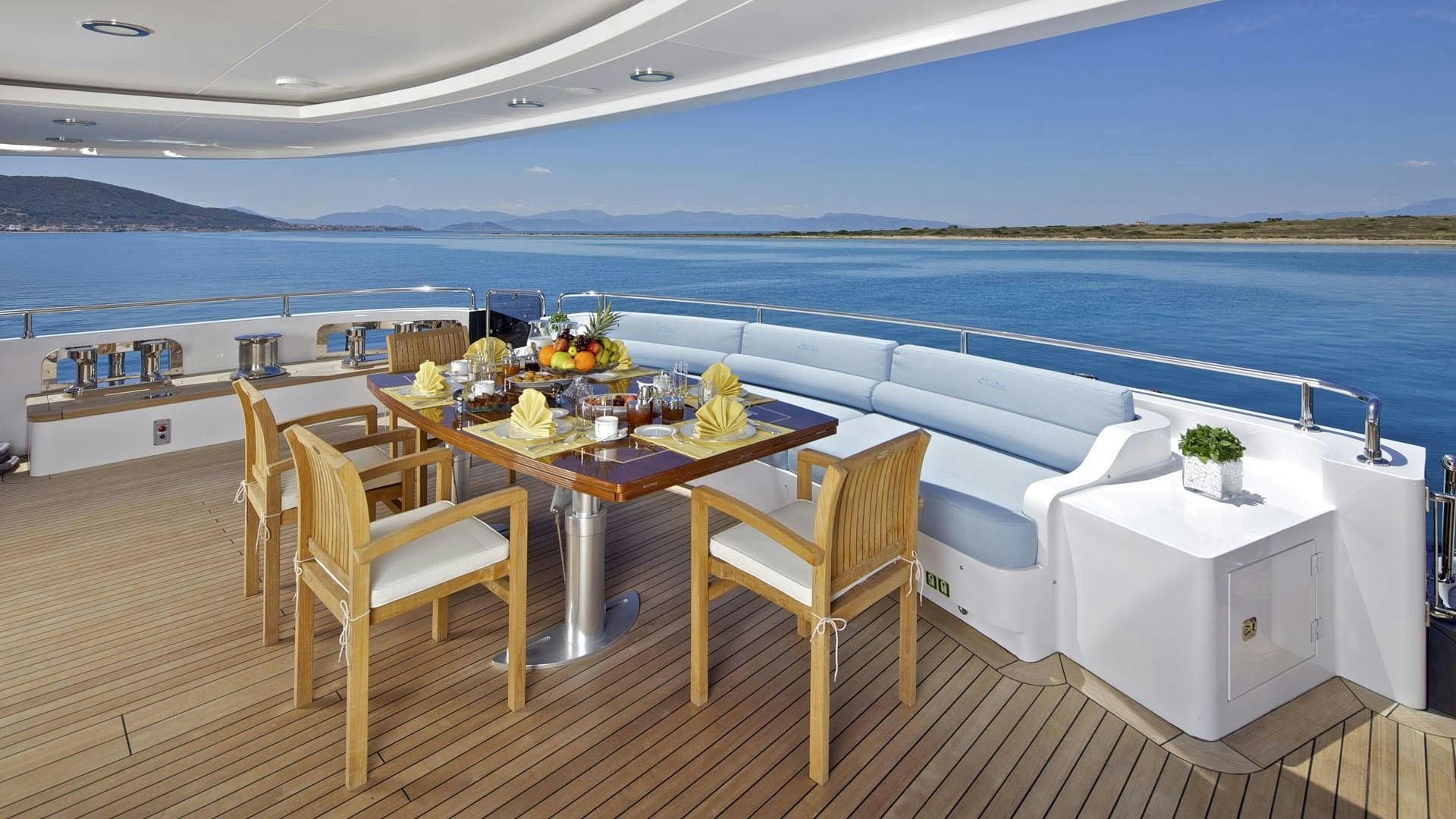 a table and chairs on a balcony overlooking a body of water aboard MIA RAMA Yacht for Charter