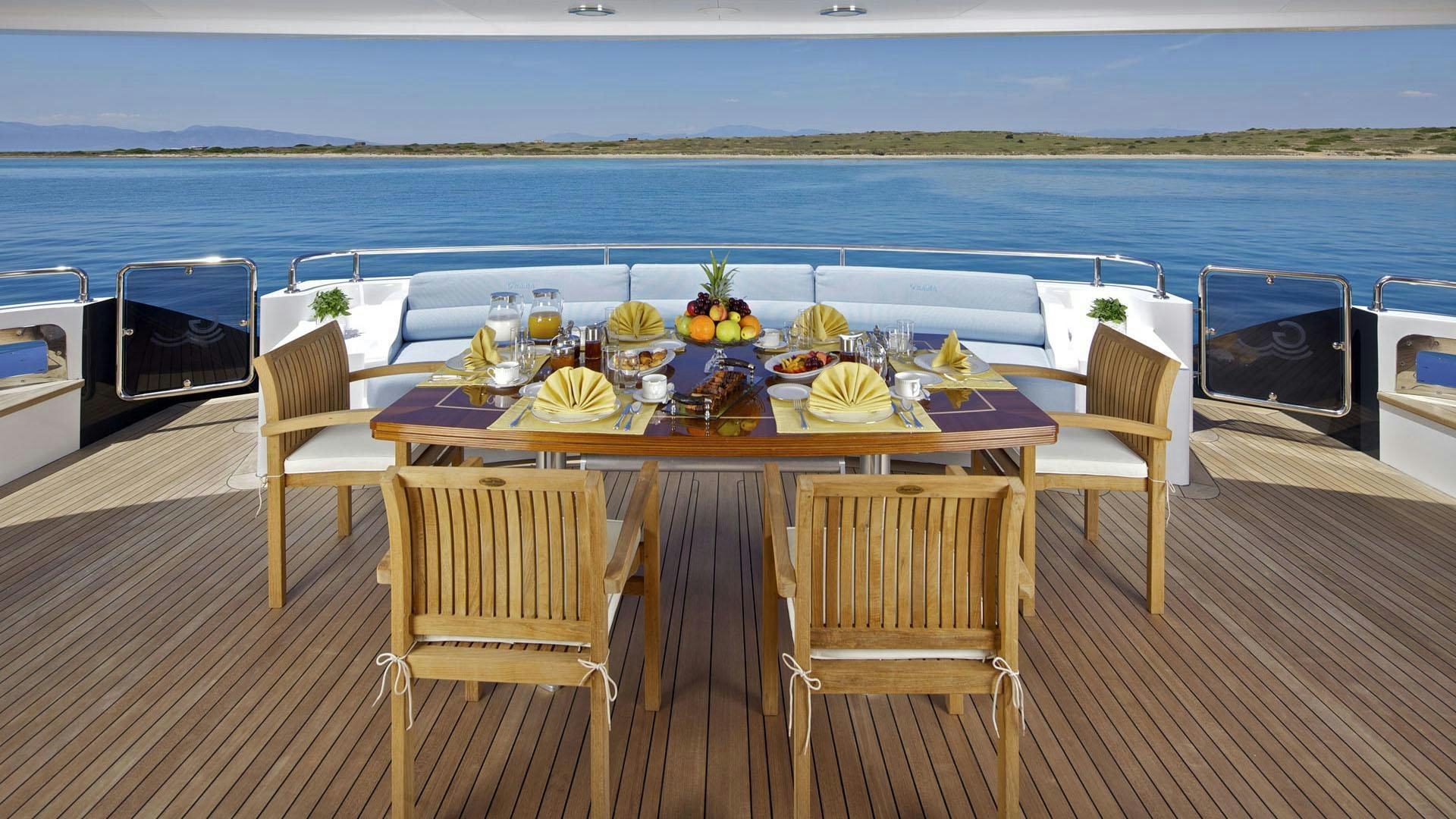 a table on a deck with chairs and food on it aboard MIA RAMA Yacht for Charter