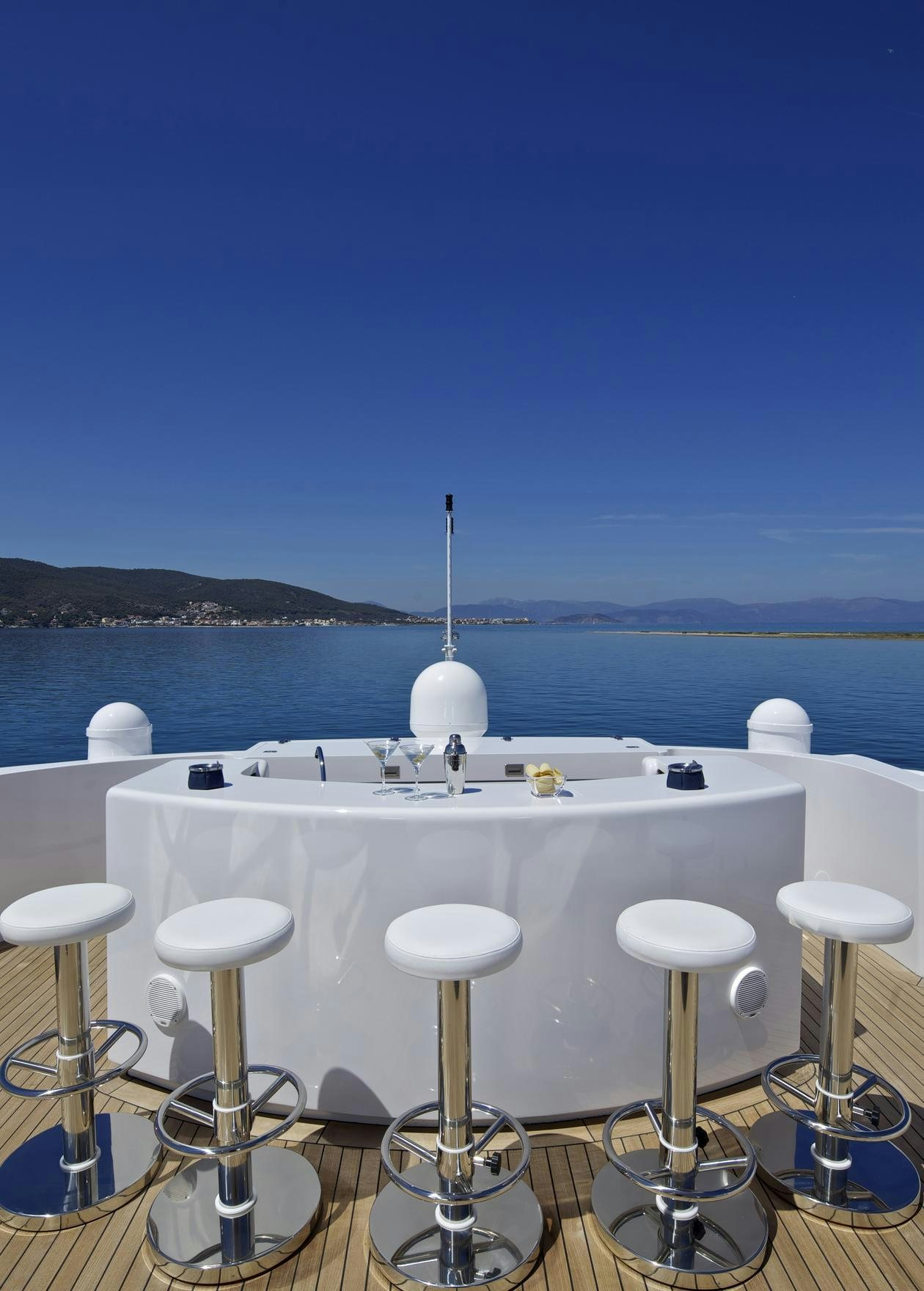 a white table with stools and stools by a body of water aboard MIA RAMA Yacht for Charter