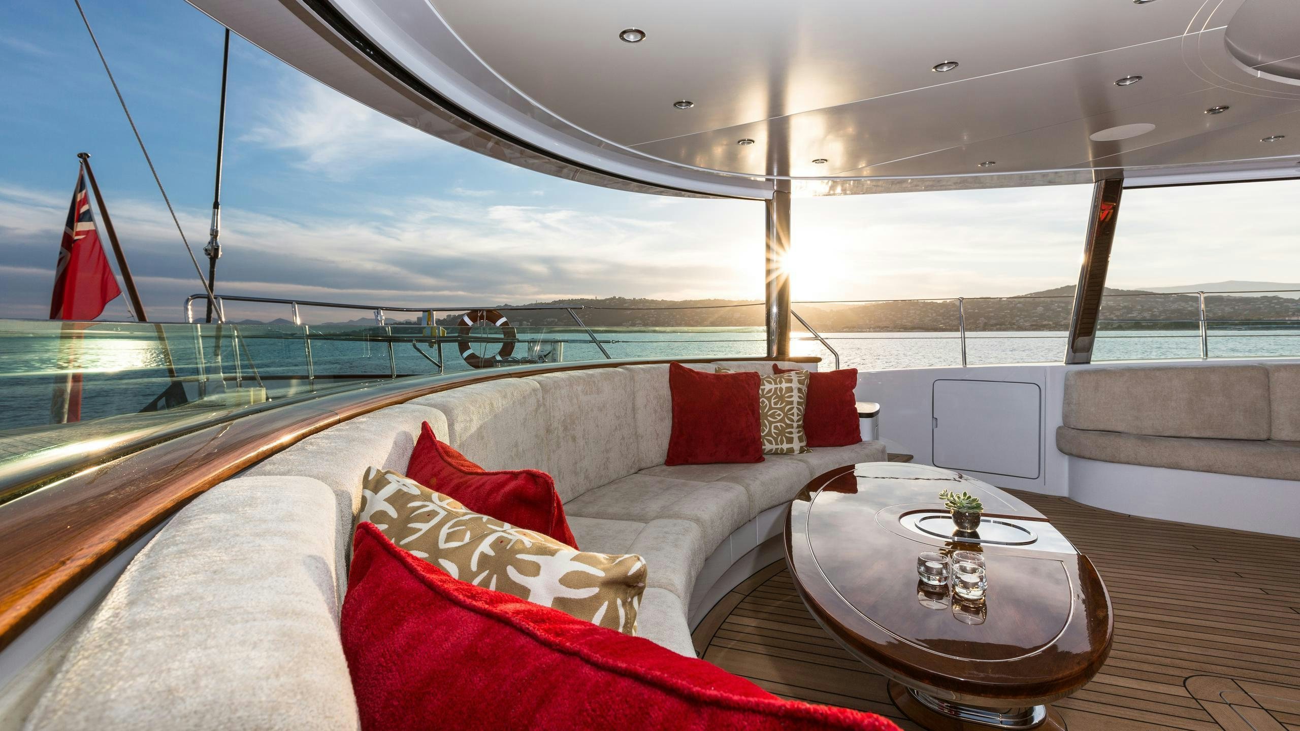 a large white couch with pillows on it and a table on a boat aboard Q Yacht for Charter