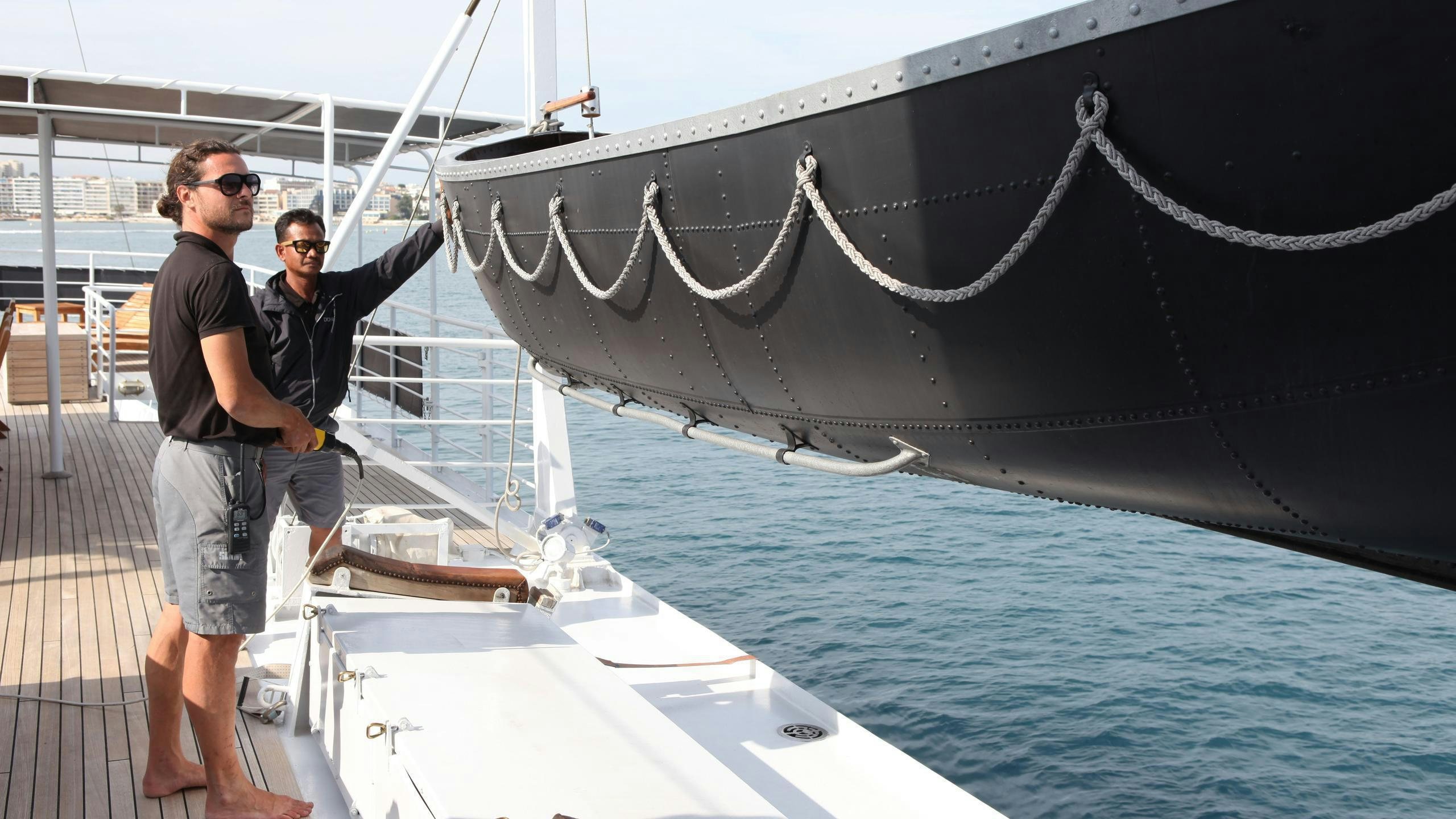 two men standing next to a large sailboat aboard DIONEA Yacht for Charter