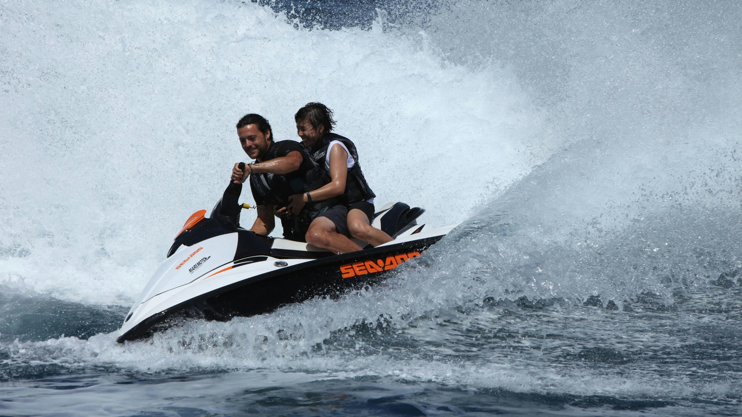 a man and woman riding a jet ski aboard DIONEA Yacht for Charter