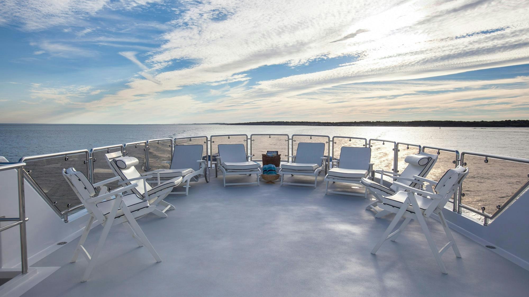 a large white deck with chairs on it and a body of water in the background aboard CHANTAL MA VIE Yacht for Charter