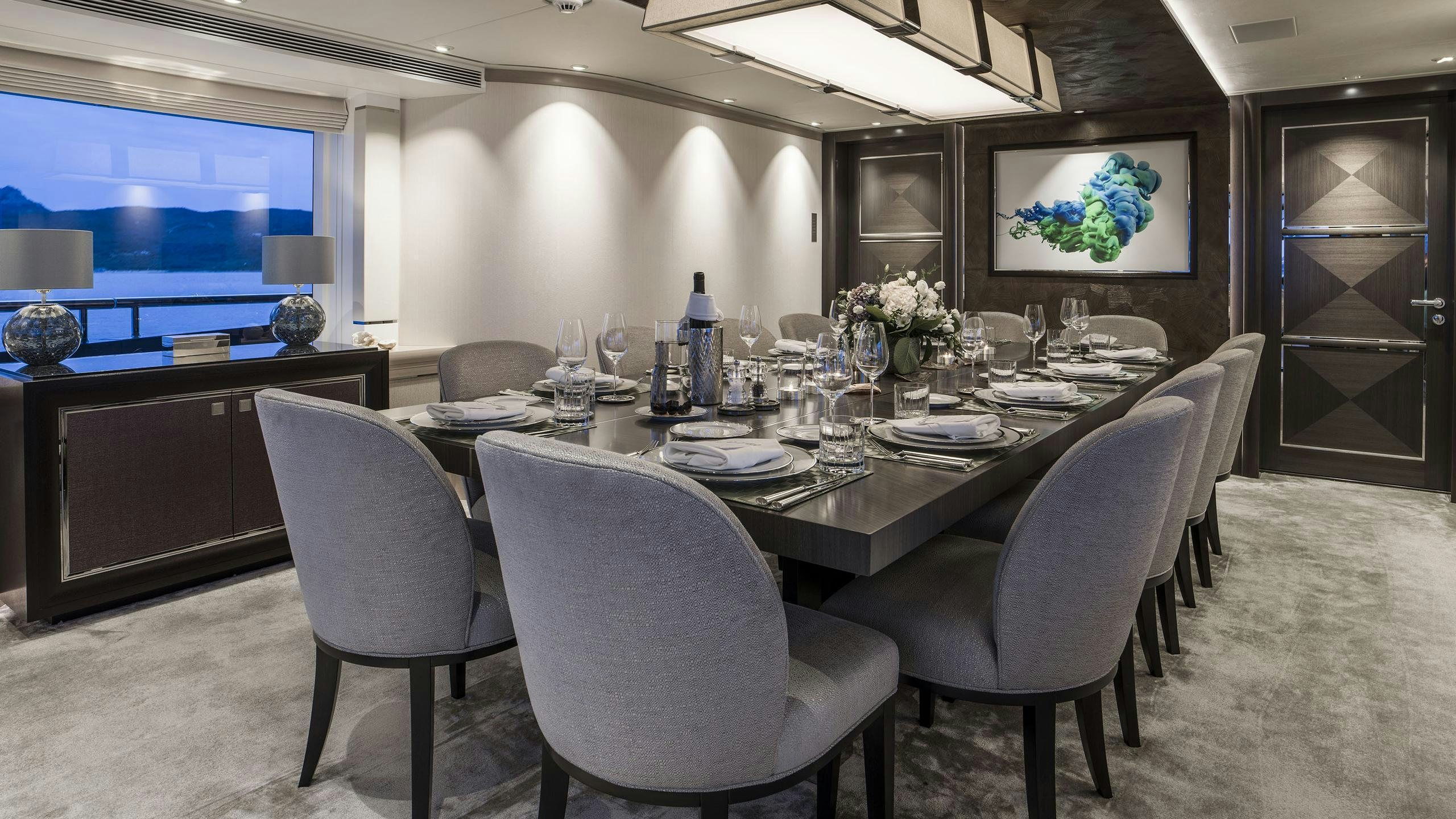 a large dining table with white chairs aboard IRISHA Yacht for Charter