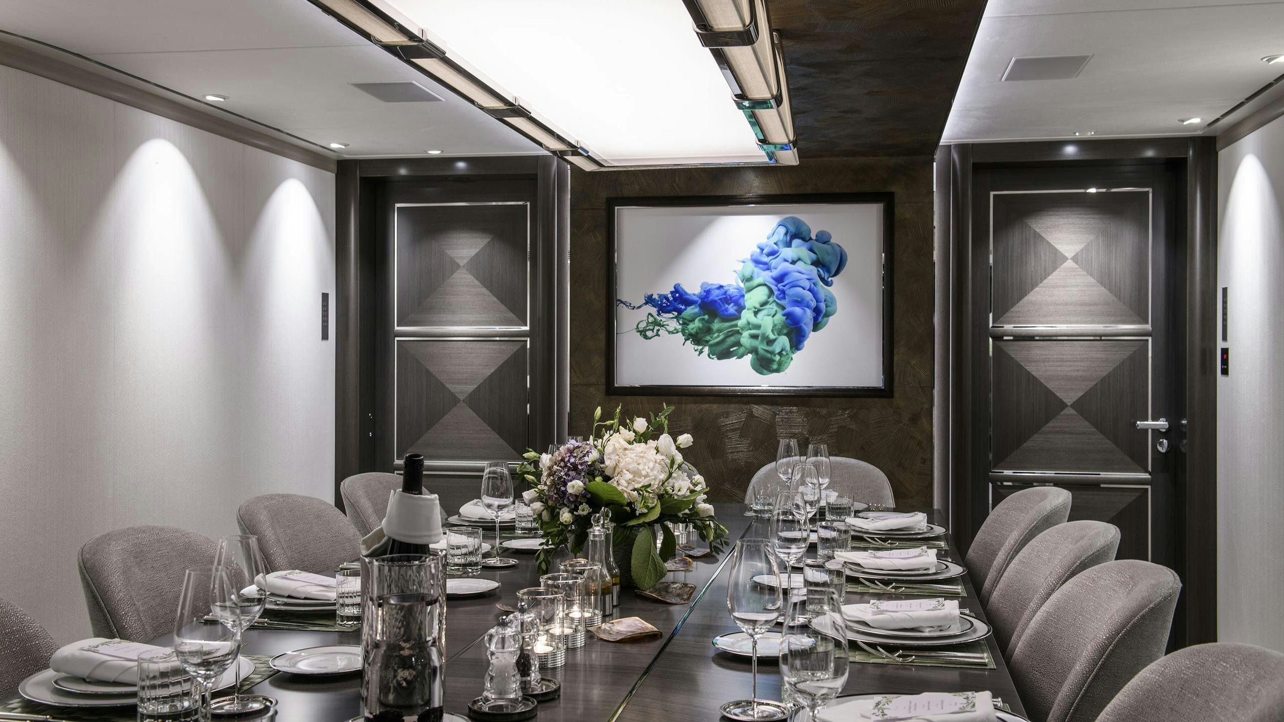 a dining table with a vase of flowers and a painting on the wall aboard IRISHA Yacht for Charter