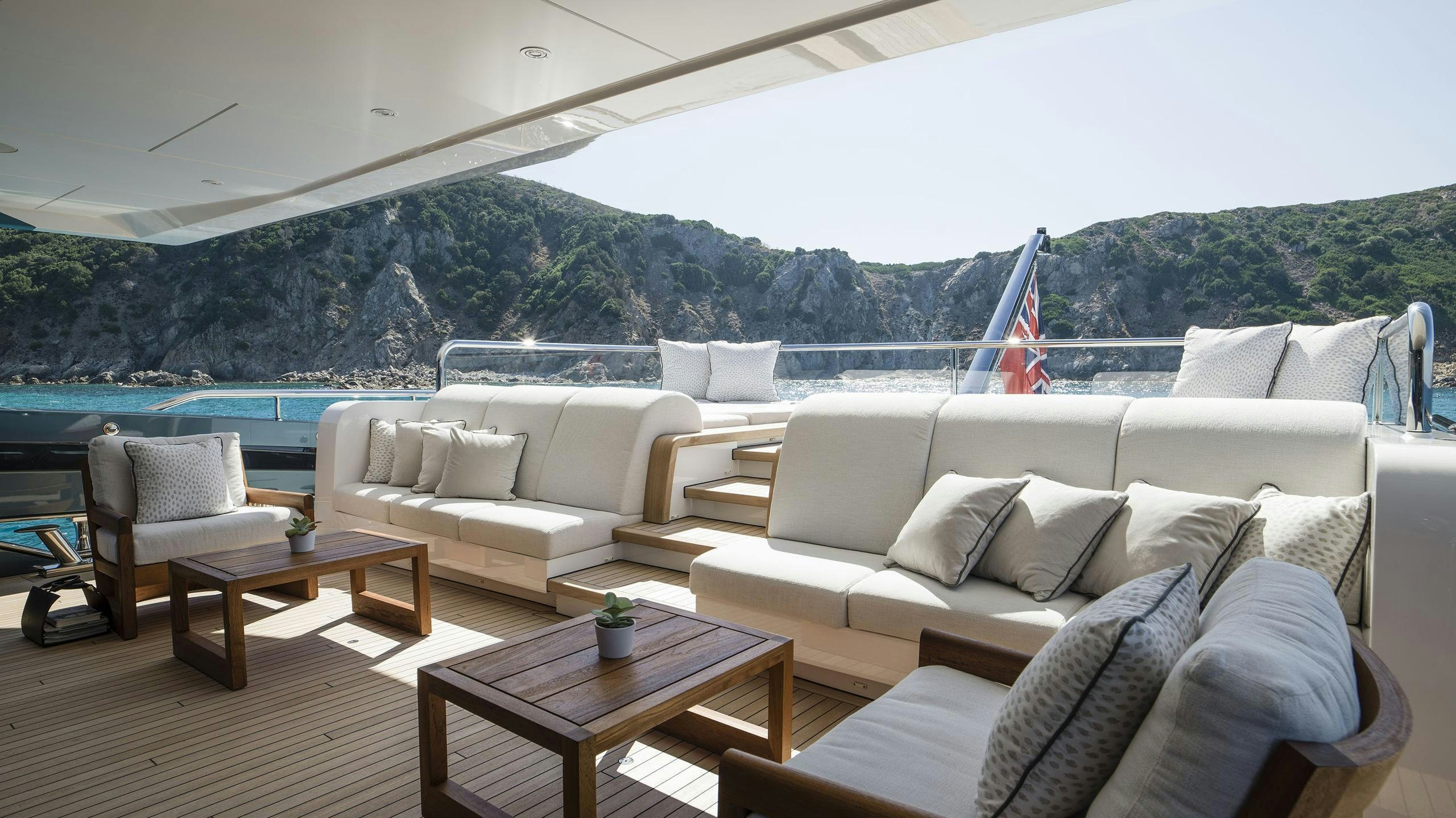 a living room with a large body of water and mountains in the background aboard IRISHA Yacht for Charter