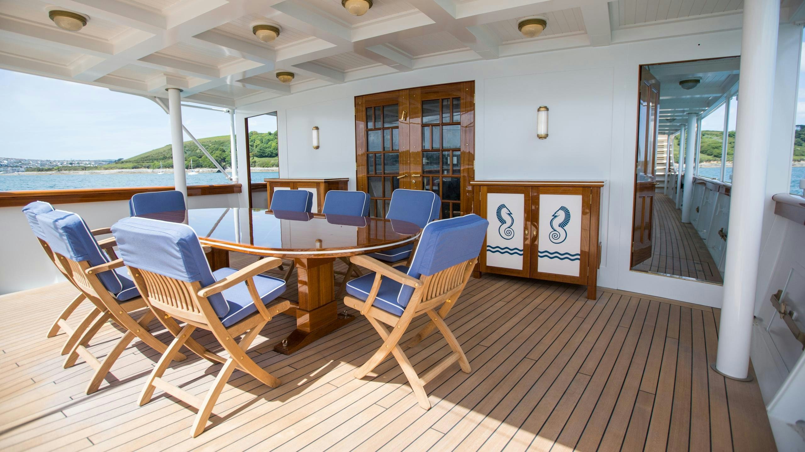 a person sitting in a chair on a deck with a pool and a deck with a view of aboard MALAHNE Yacht for Charter
